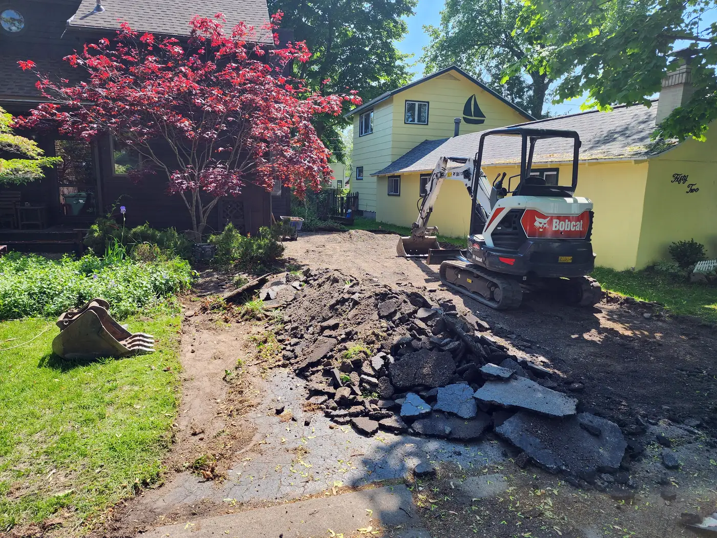 Mini excavator tearing out an old asphalt driveway