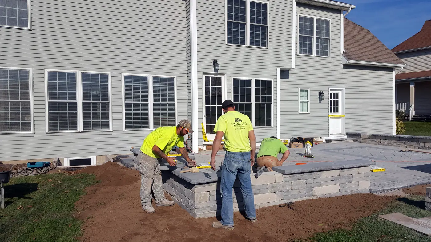 Pavers Plus crew building a raised paver patio with a seat wall