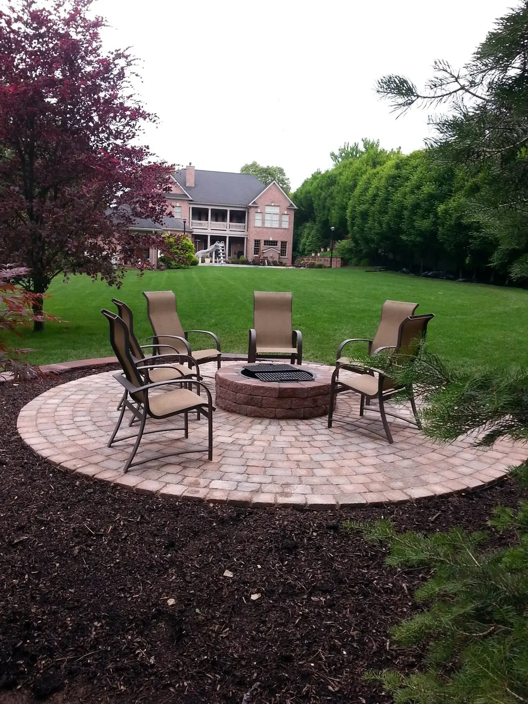 Round paver patio with a fire pit and seating