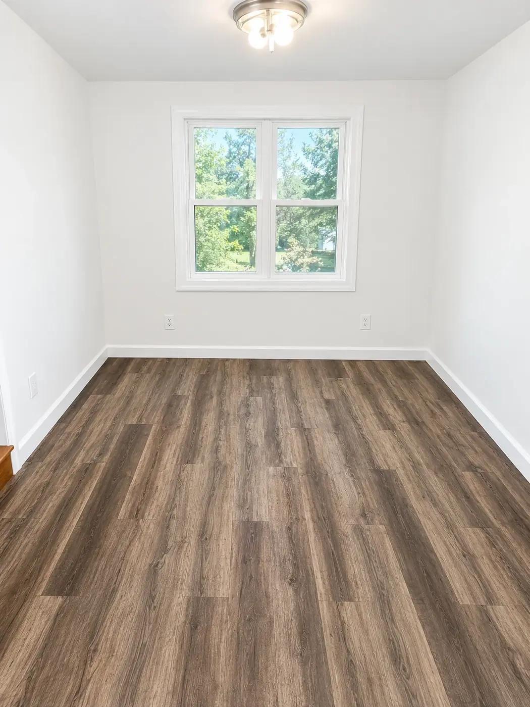 Bedroom with new wood look vinyl plank flooring and freshly painted white walls