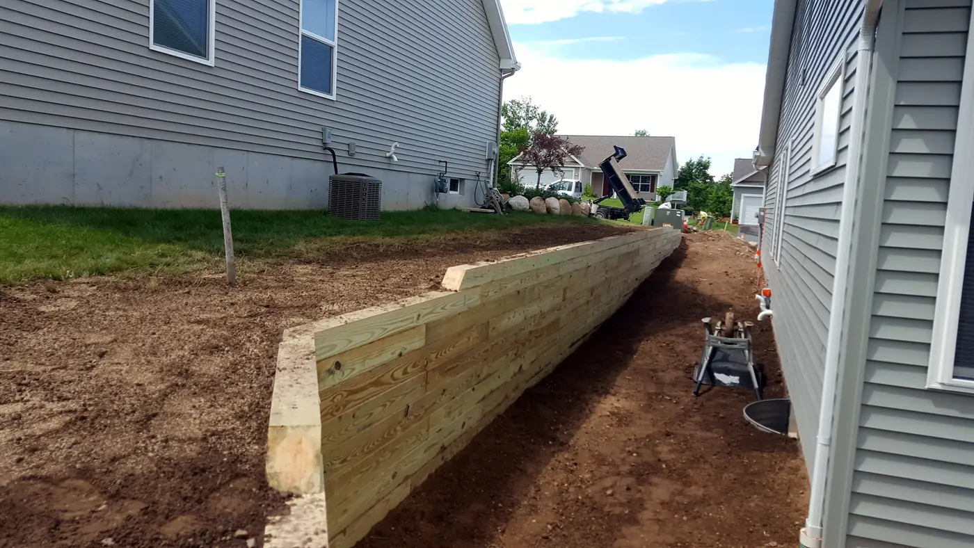 Yard regraded along the side of a house with a new timber retaining wall