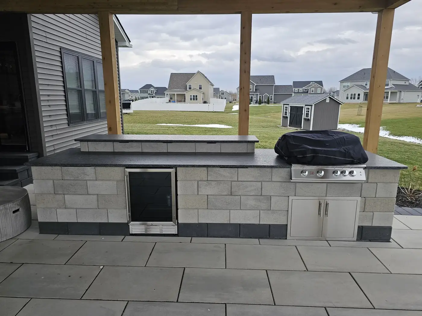 Stone outdoor kitchen counter with a built in grill under a covered patio