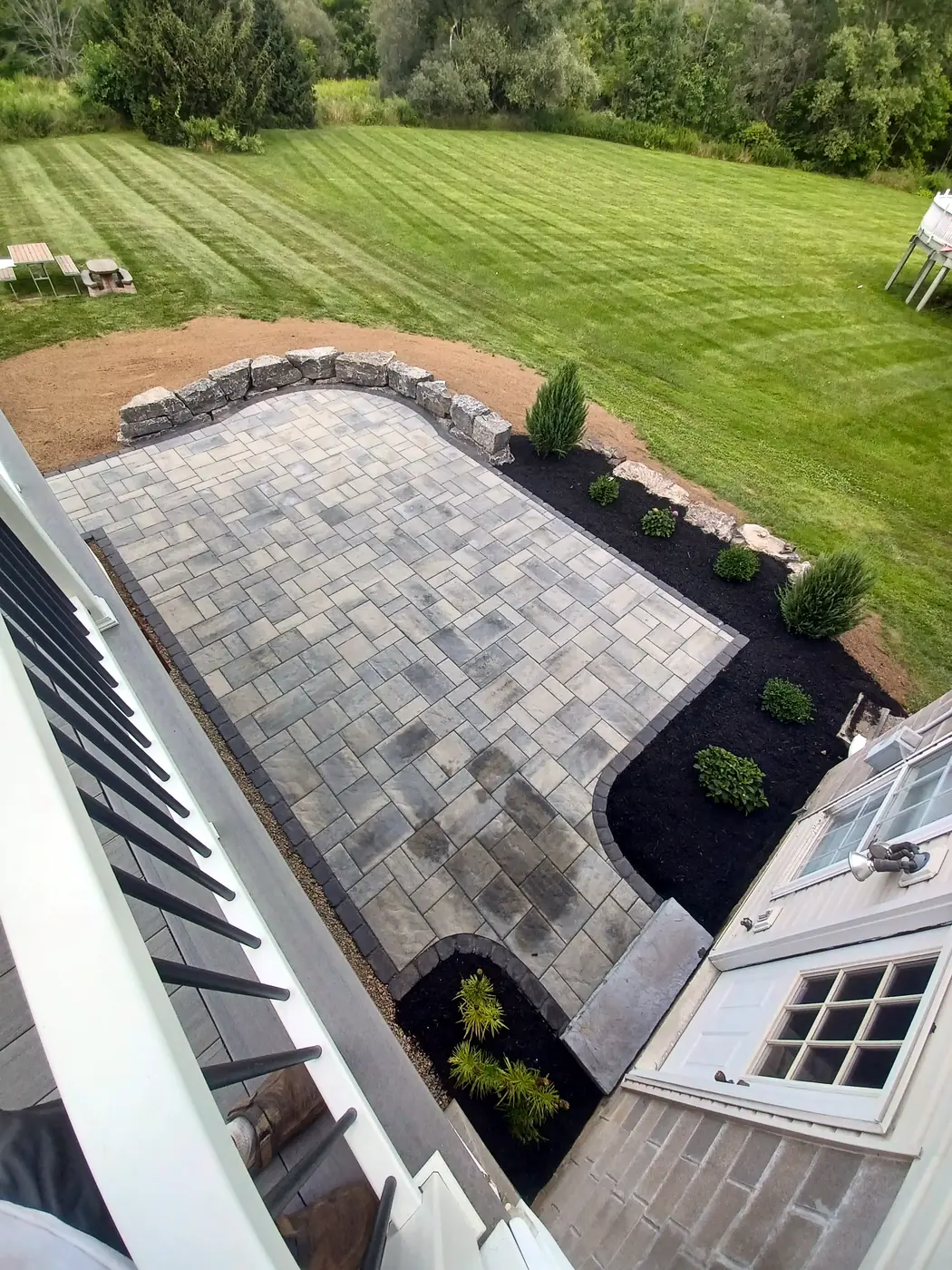 Aerial view of a patio with a stone wall, mulch beds and new plantings
