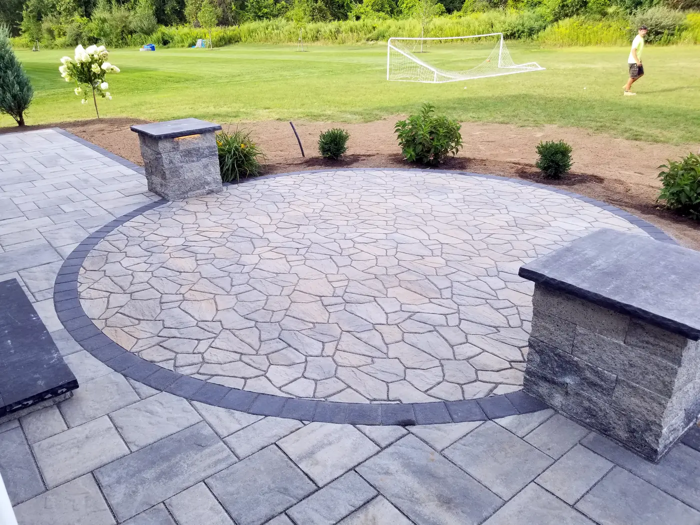 Round flagstone style paver patio with a border and two stone pillars