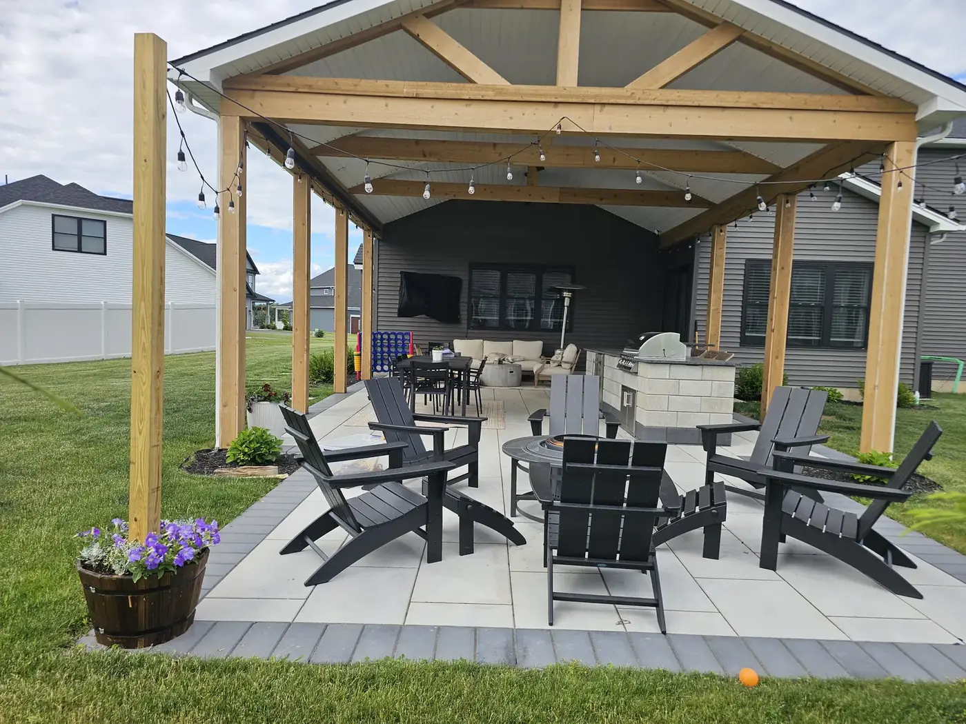 Paver patio under a cedar pavilion with chairs around a fire pit